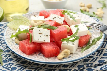 Delicious watermelon salad with feta cheese, cashew nuts and spices served on light table, closeup