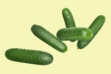 Whole ripe cucumbers flying on beige background