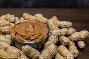 Bowl of peanut butter surrounded by peanuts.