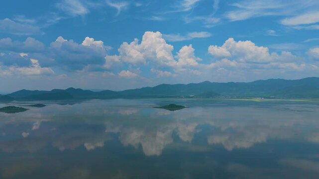 Mirrored majesty: Aerial journey over Cuitzeo Lake's revitalized waters, showcasing stunning symmetry as azure hues and fluffy clouds harmonize in perfect reflection