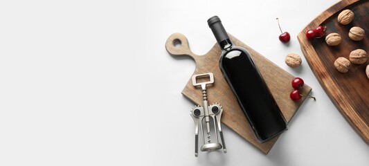 Composition with bottle of wine, corkscrew, walnuts and cherries on white background with space for text, top view