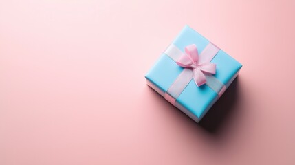 A beautifully wrapped blue gift box with a pink ribbon rests on a soft pink surface, perfect for celebrations.