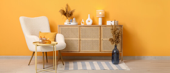 Interior of living room with armchair, commode and decorative pumpkins