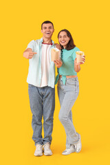 Obraz premium Beautiful young couple with french fries on yellow background