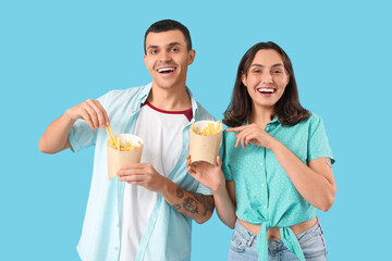 Young couple with french fries on blue background