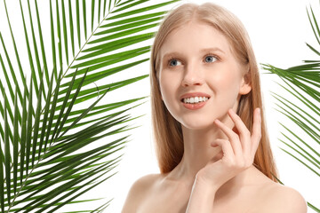 Fototapeta premium Young blonde woman and palm leaves on white background, closeup