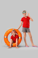Happy little children lifeguards with ring buoy showing OK gesture on grey background