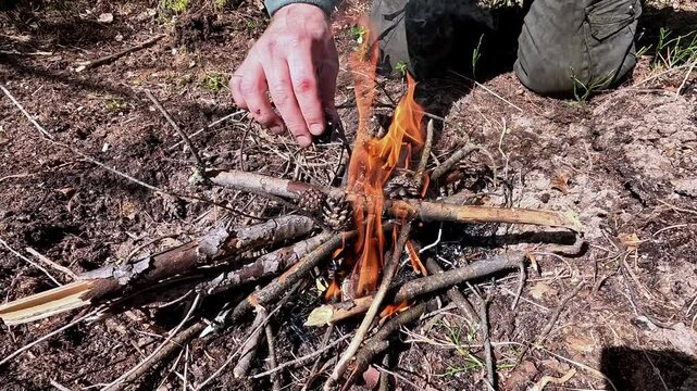 a man in the forest lights a fire