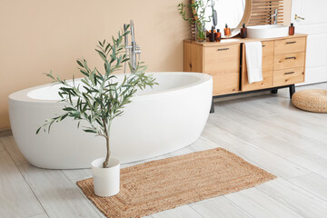 Interior of light bathroom with bathtub, ceramic sink and chest of drawers