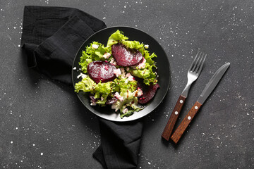 Plate of fresh salad with beet and cottage cheese on black background
