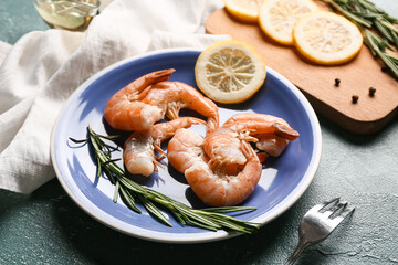 Plate with tasty boiled shrimps, lemon and rosemary on green background