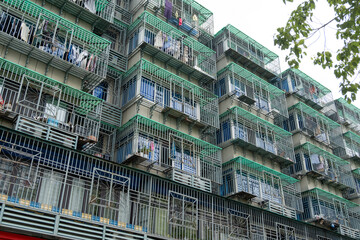 A densely populated and weathered apartment building with numerous balconies and windows, featuring...