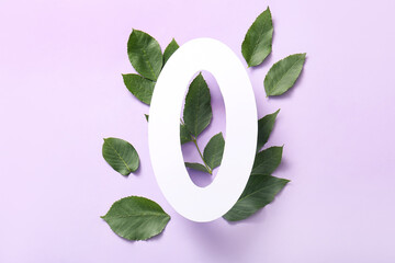 Green leaves with paper number zero on lilac background. Top view
