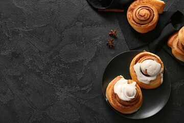 Plate of sweet cinnamon rolls with glaze and star anise on black background © Pixel-Shot