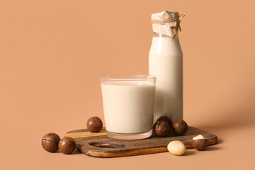 Glass and bottle of fresh macadamia milk on brown background