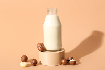 Decorative podium with bottle of fresh macadamia milk on brown background