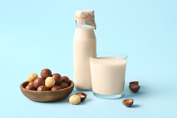 Glass and bottle of fresh macadamia milk on blue background