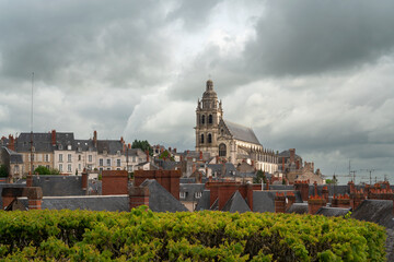 View of St. Louis Cathedral towering over the roofs of ancient houses on a sunny summer day, Blois,...