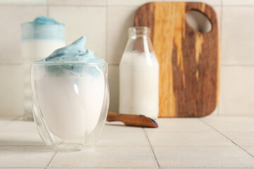 Glass of blue dalgona matcha latte on tile table, closeup