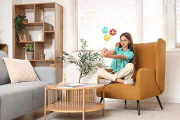 Teenage girl with toy windmill sitting in armchair at home