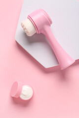 Fototapeta premium Plaster stand, facial massage brush and jar of cosmetic product on pink background, closeup