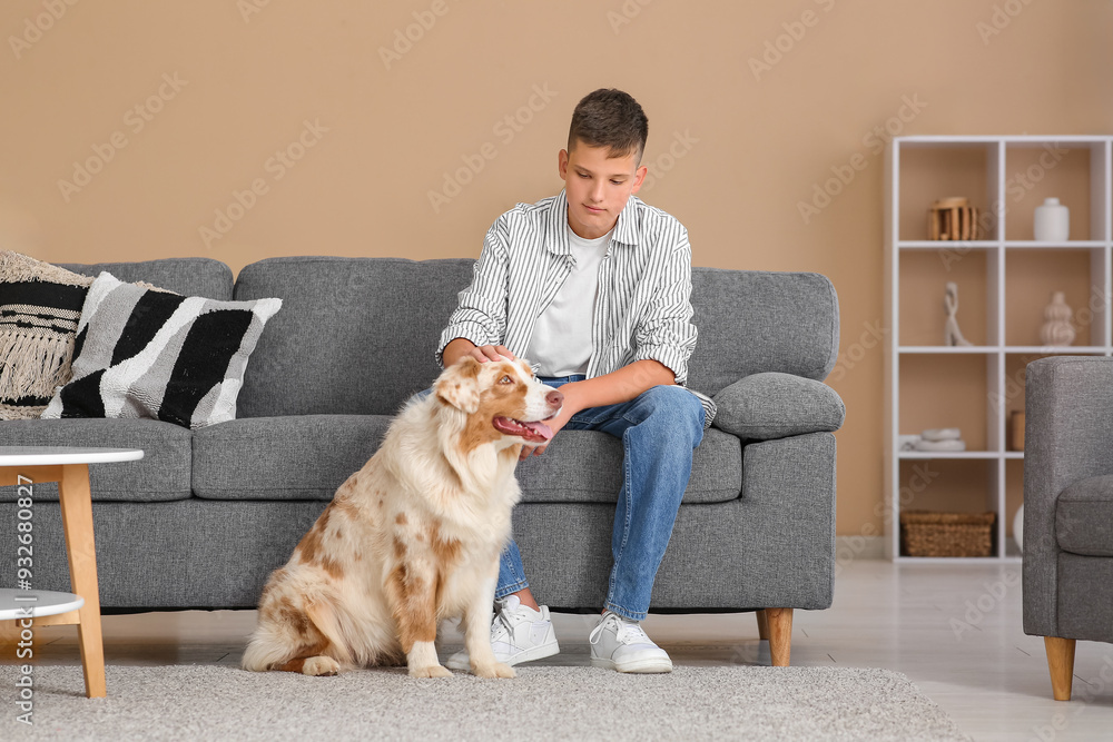 Canvas Prints Teenage boy with Australian Shepherd dog sitting on sofa at home