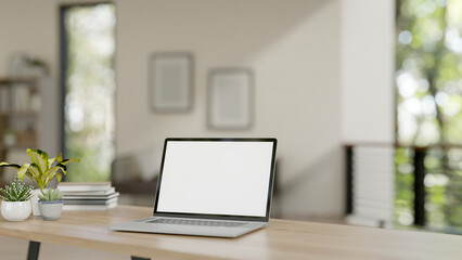 A laptop with a white-screen mockup on a wooden table in a contemporary home. home workspace