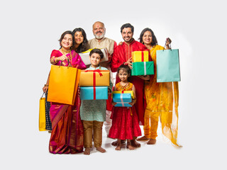 Happy Indian family with kids and elders holding shopping bags and gifts for Diwali or wedding