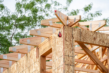 New residential home construction in framing stage, looking up at red chalk line reel hanging from...