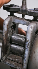 Goldsmith is using a rolling mill to shape metal for jewelry making