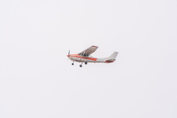 Small ultralight airplane with overhead wing and single propeller flying in sunset sky.