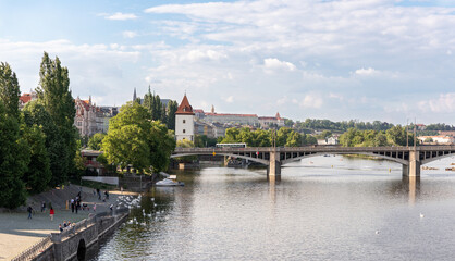 Obraz premium Irasekov Bridge on the Vltava River and the embankment with the ancient houses in Prague in Czech Republic