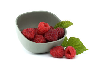 Fresh raspberries in a grey bowl with leaves on white background