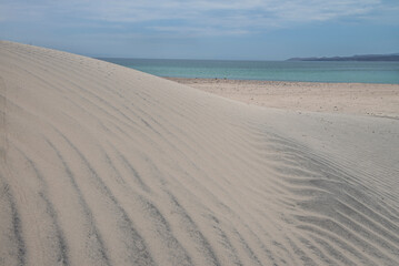 Tecolote Beach, La Paz Baja California Sur. Mexico, on a cloudy summer morning, by the sea of cortes with dunes in the foreground and blue sea in the background