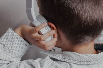 Close up of a little boy listening to music with white headphones.