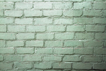 A brick wall of a green shade with contrasting lighting. Old brickwork.
