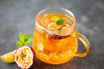 Fruit ice tea. Refreshing summer drink with syrup, passion fruit, lime, mint and ice. Glass with...