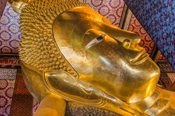Colorful face Reclining Buddha, Wat Pho Temple, Bangkok, Thailand. Temple built in 1600's. Reclining Buddha built in 1832. Face reflects Buddha entry into heaven nirvana final goal of Buddhism.