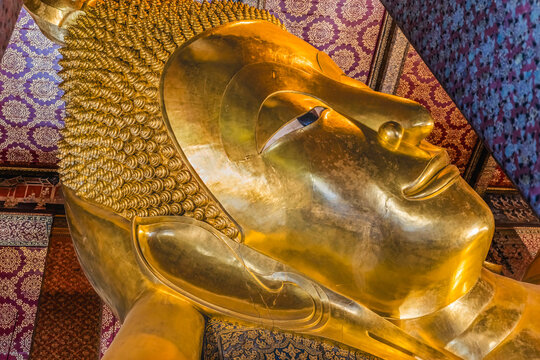 Colorful face Reclining Buddha, Wat Pho Temple, Bangkok, Thailand. Temple built in 1600's. Reclining Buddha built in 1832. Face reflects Buddha entry into heaven nirvana final goal of Buddhism.