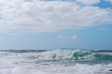 Waves Crashing on Sunny Beach Under  Partly Cloudy Sky in Afternoon