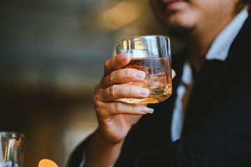 A young businessman holds a glass of whiskey, toasting with friends at an upscale bar. The scene captures the essence of luxury and celebration, with a focus on camaraderie and the nightlife atmospher