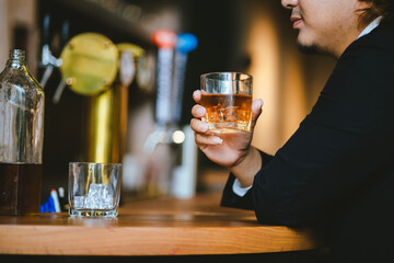 A young businessman holds a glass of whiskey, toasting with friends at an upscale bar. The scene captures the essence of luxury and celebration, with a focus on camaraderie and the nightlife atmospher