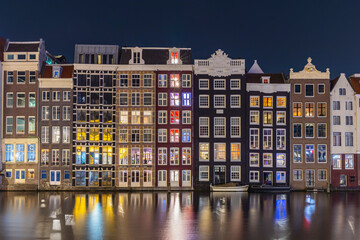 Netherlands, North Holland, Amsterdam. Lights at night in traditional row houses on a canal in Amsterdam.