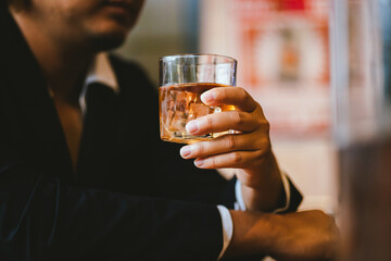 A young businessman holds a glass of whiskey, toasting with friends at an upscale bar. The scene captures the essence of luxury and celebration, with a focus on camaraderie and the nightlife atmospher