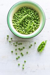 Peeled green peas in a white bowl. Kitchen scene.