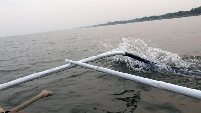First-person view of the sea from a sailing boat whose outriggers banging against the waves