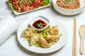 Pan fried dumplings with dipping sauce, pork chop, minced pork rice served in plate isolated on marble background side view of taiwan food