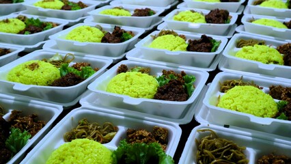 Large amount packages of yellow rice, noodles, and grilled chicken served in foam food container