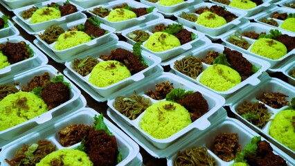 Large amount packages of yellow rice, noodles, and grilled chicken served in foam food container