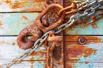 Rusty lock and chain on light blue wood.